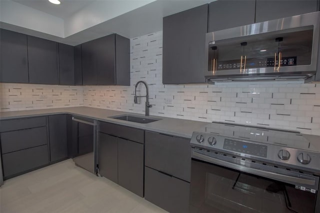 kitchen with stainless steel appliances, a sink, modern cabinets, decorative backsplash, and gray cabinets
