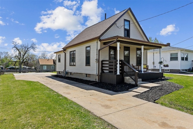 view of front of property featuring a porch, driveway, a front yard, and roof with shingles