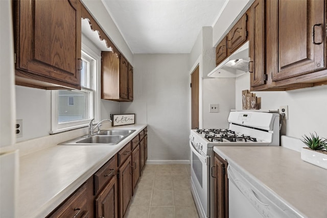 kitchen featuring white appliances, a sink, under cabinet range hood, light countertops, and light tile patterned floors