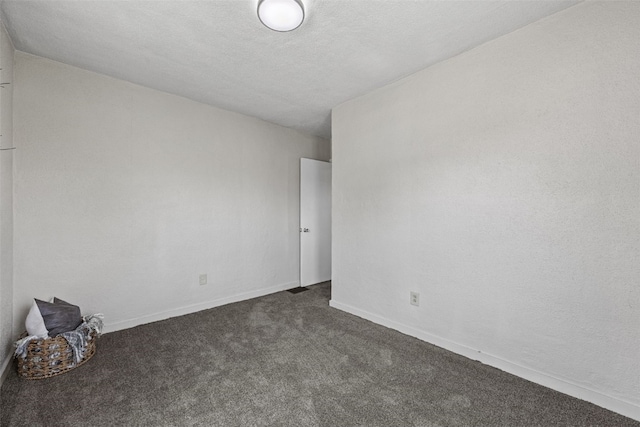 spare room with dark carpet and baseboards