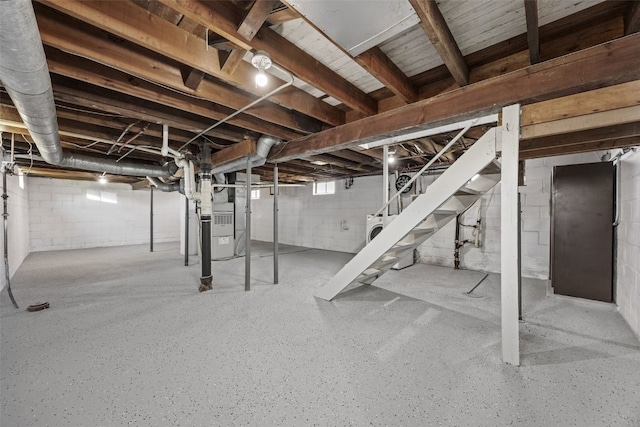 unfinished basement featuring stairs and heating unit