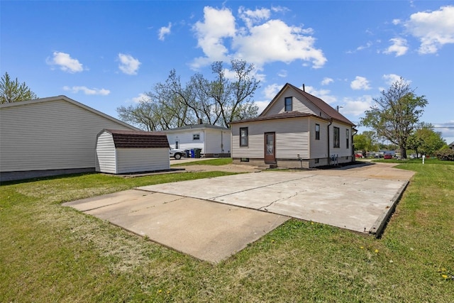 back of property featuring a yard, an outbuilding, and a storage unit