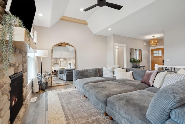 living room featuring wood finished floors, a stone fireplace, ceiling fan, a chandelier, and recessed lighting