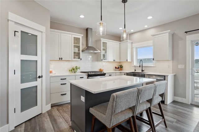 kitchen with wall chimney exhaust hood, a sink, electric stove, a kitchen bar, and backsplash