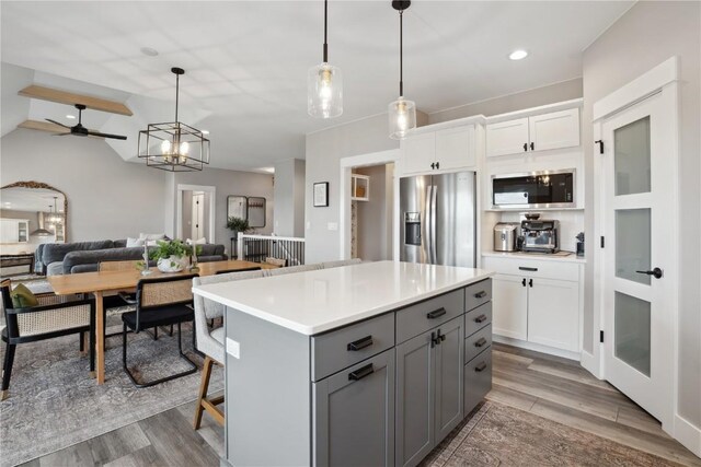 kitchen featuring stainless steel appliances, gray cabinetry, open floor plan, light countertops, and white cabinets