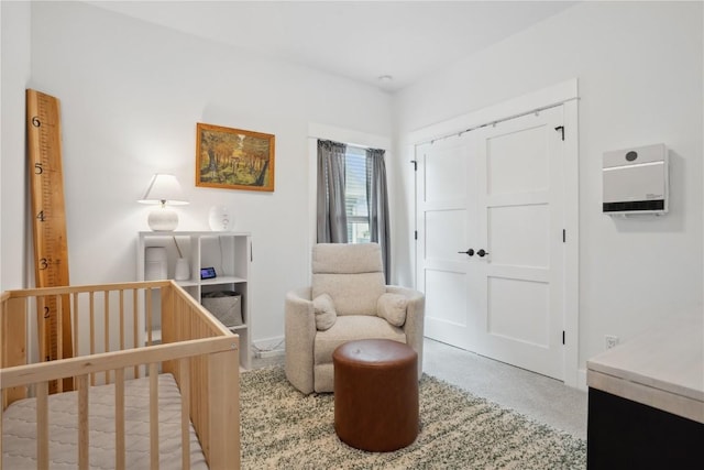 bedroom with a nursery area, carpet floors, a closet, and heating unit