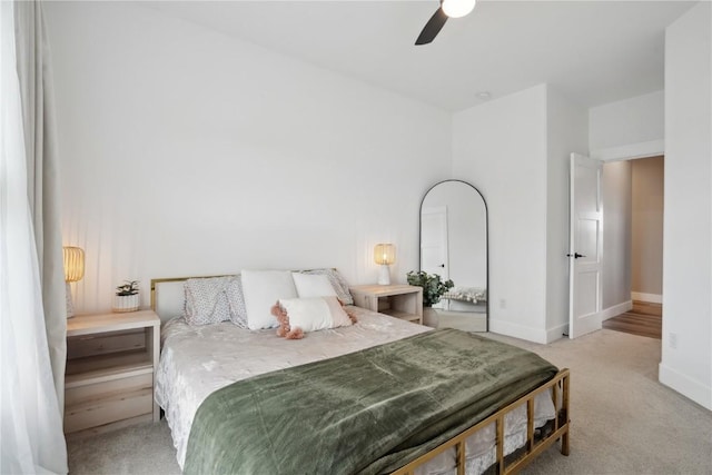 bedroom with light carpet, baseboards, and a ceiling fan