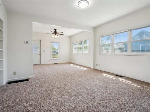 carpeted empty room featuring a ceiling fan and baseboards