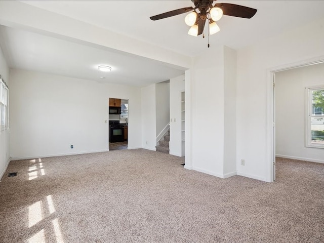 unfurnished living room with carpet floors, a ceiling fan, baseboards, and stairway