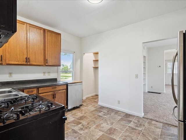 kitchen with appliances with stainless steel finishes, baseboards, dark countertops, and brown cabinets