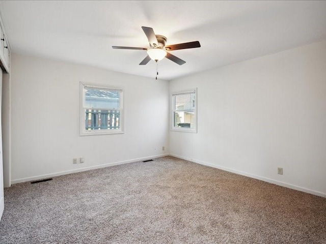 carpeted spare room featuring a ceiling fan and baseboards
