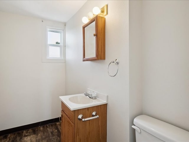 half bathroom with toilet, vanity, and wood finished floors