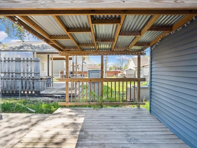 wooden deck featuring a shed, an outdoor structure, and fence