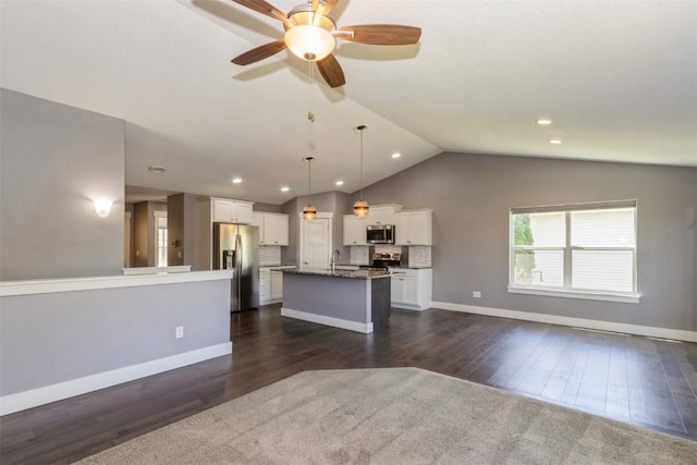 kitchen with appliances with stainless steel finishes, open floor plan, a kitchen island with sink, a sink, and white cabinetry