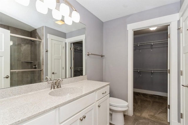 full bath with a stall shower, toilet, vanity, a spacious closet, and baseboards