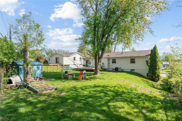view of green lawn featuring a shed, central AC, and an outdoor structure