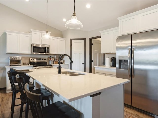 420 Dawson Dr, West Branch, IA 52358 - kitchen with stainless steel appliances, white cabinetry, a center island with sink, lofted ceiling, and decorative light fixtures