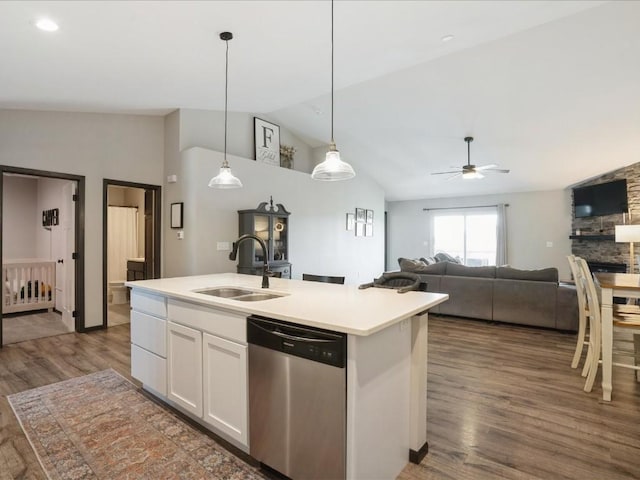 kitchen with stainless steel dishwasher, a sink, vaulted ceiling, white cabinetry, and dark wood-type flooring