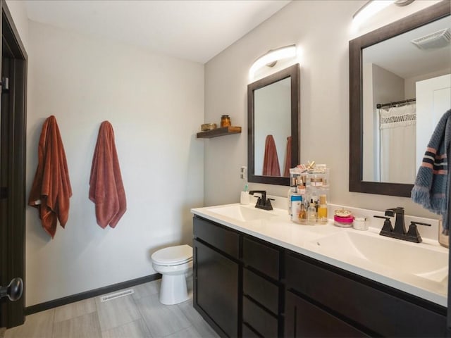 full bath featuring toilet, double vanity, and baseboards