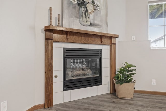 detailed view of wood finished floors, a fireplace, and baseboards