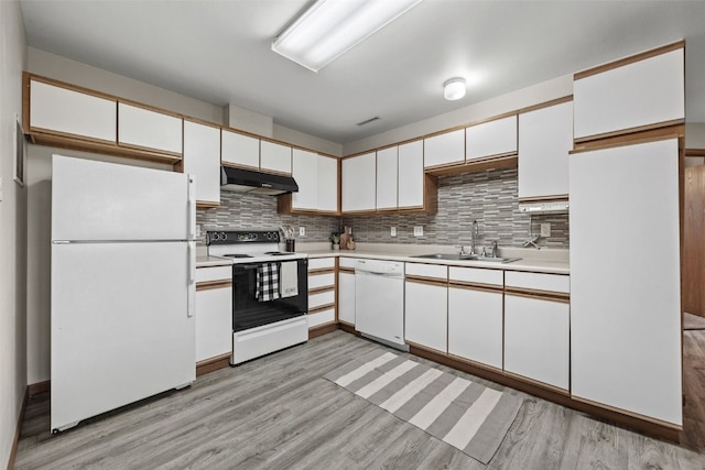 kitchen with white appliances, a sink, light countertops, under cabinet range hood, and white cabinetry