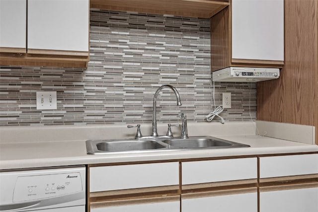 kitchen featuring white dishwasher, a sink, backsplash, and light countertops