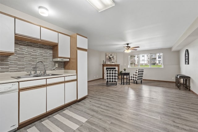 kitchen with dishwasher, a sink, a ceiling fan, light countertops, and tasteful backsplash