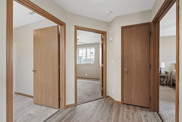 corridor with light wood-style flooring and baseboards