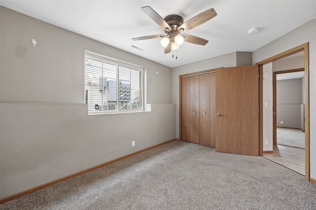 unfurnished bedroom with carpet flooring, a closet, baseboards, and a ceiling fan