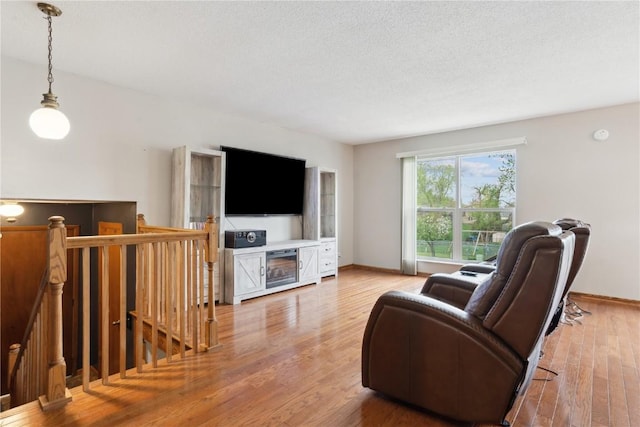living room featuring baseboards, wood finished floors, and a textured ceiling