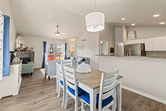 1227 Mary Ln, North Liberty, IA 52317 - dining room with light wood-type flooring, lofted ceiling, ceiling fan, a fireplace, and recessed lighting