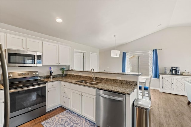 1227 Mary Ln, North Liberty, IA 52317 - kitchen with stainless steel appliances, a sink, light wood finished floors, vaulted ceiling, and white cabinetry