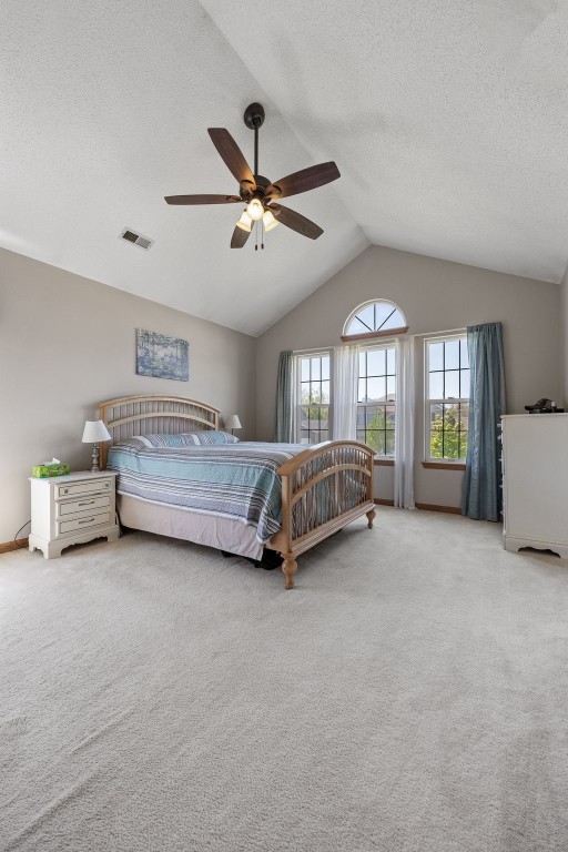 carpeted bedroom with vaulted ceiling, a textured ceiling, and ceiling fan