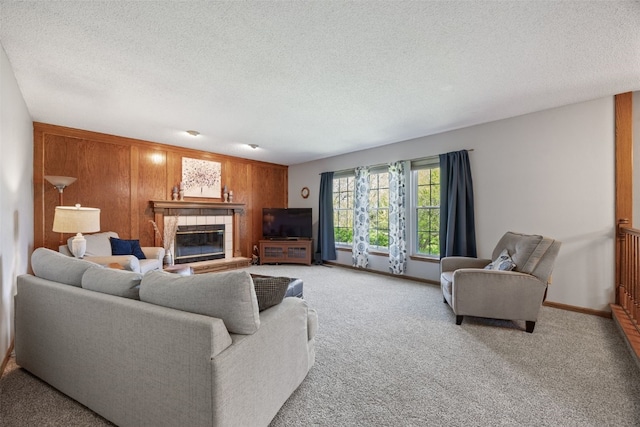 living area with a fireplace, a textured ceiling, carpet floors, and wood walls