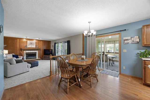 dining area featuring plenty of natural light, light wood-style floors, a fireplace, a chandelier, and a textured ceiling