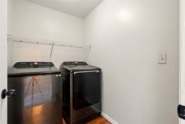laundry room featuring independent washer and dryer, baseboards, and wood finished floors