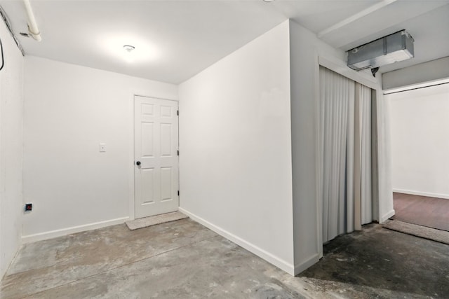 empty room featuring unfinished concrete floors and baseboards