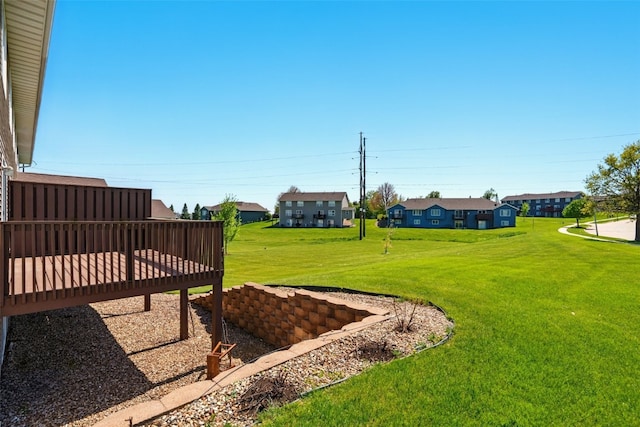 view of grassy yard with a wooden deck and a residential view