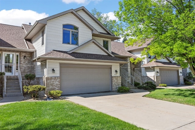view of front of house featuring brick siding, a garage, driveway, and a front lawn