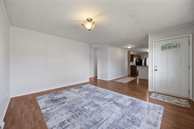 unfurnished living room featuring dark wood-style floors, baseboards, and ornamental molding