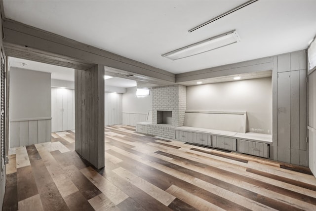 finished below grade area featuring wood finished floors, a fireplace, wainscoting, and wooden walls
