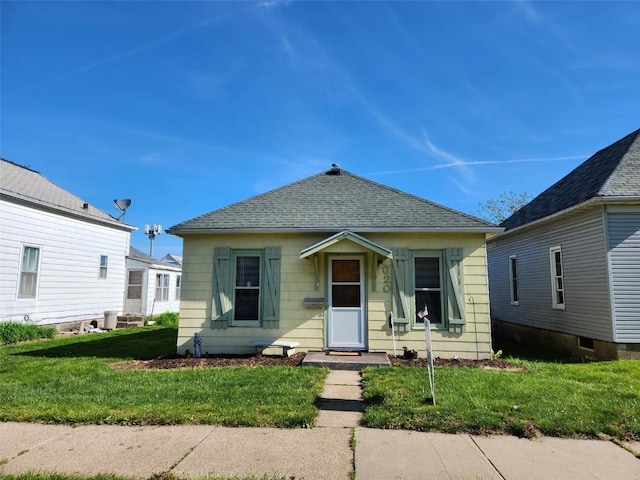 view of front of home featuring a front yard and roof with shingles