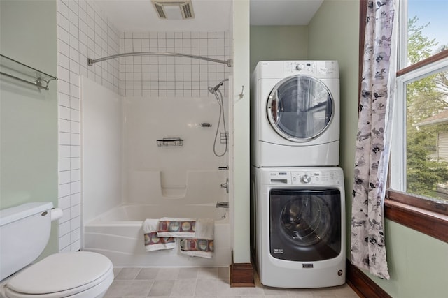 full bath with stacked washer / drying machine, toilet, and shower / bath combination
