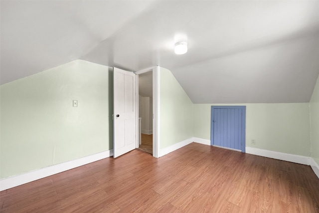 additional living space featuring wood finished floors, vaulted ceiling, and baseboards