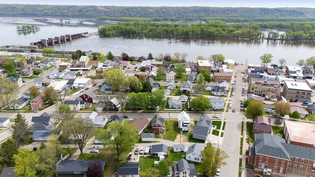 aerial view of property and surrounding area featuring a nearby body of water, a heavily wooded area, and nearby suburban area
