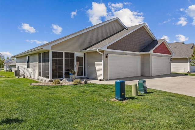 view of front of home featuring an attached garage, driveway, central AC unit, and a front yard