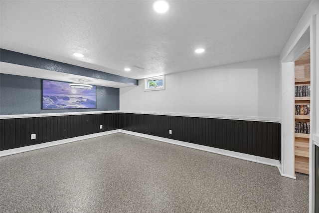 basement with wainscoting, a textured ceiling, and recessed lighting