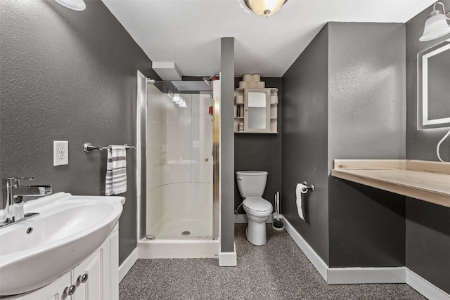 bathroom with baseboards, a stall shower, vanity, toilet, and a textured wall