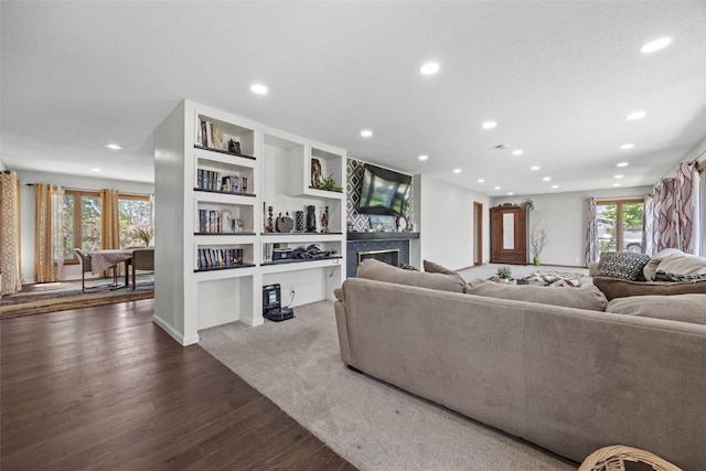 living area featuring recessed lighting, dark wood-type flooring, built in features, a fireplace, and baseboards