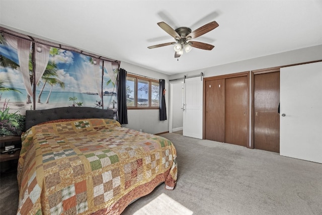 bedroom with carpet flooring, multiple closets, a barn door, ceiling fan, and baseboards